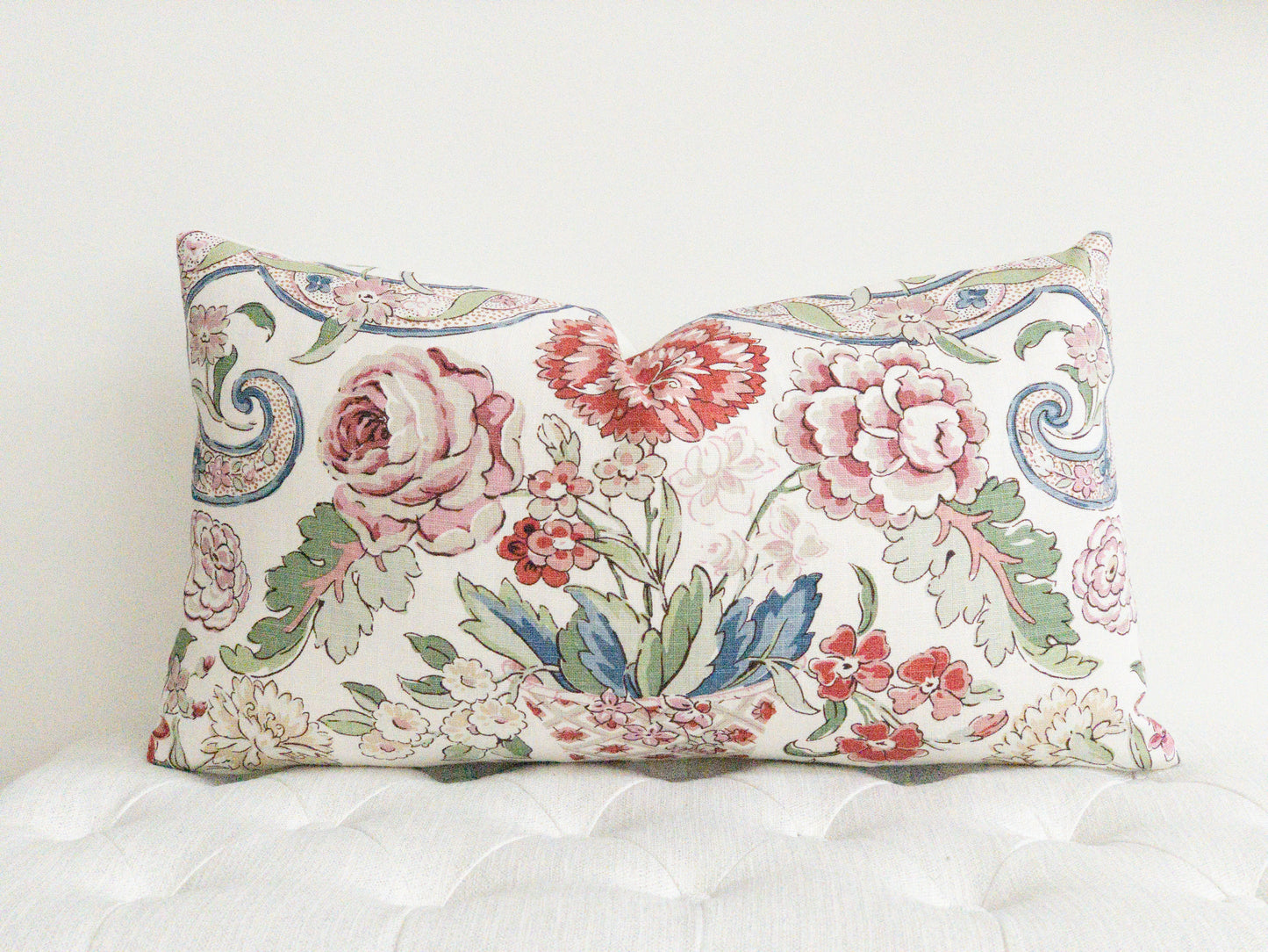 Multi color floral designer lumbar pillow.  Reds, pinks , blues and greens on a white background. 