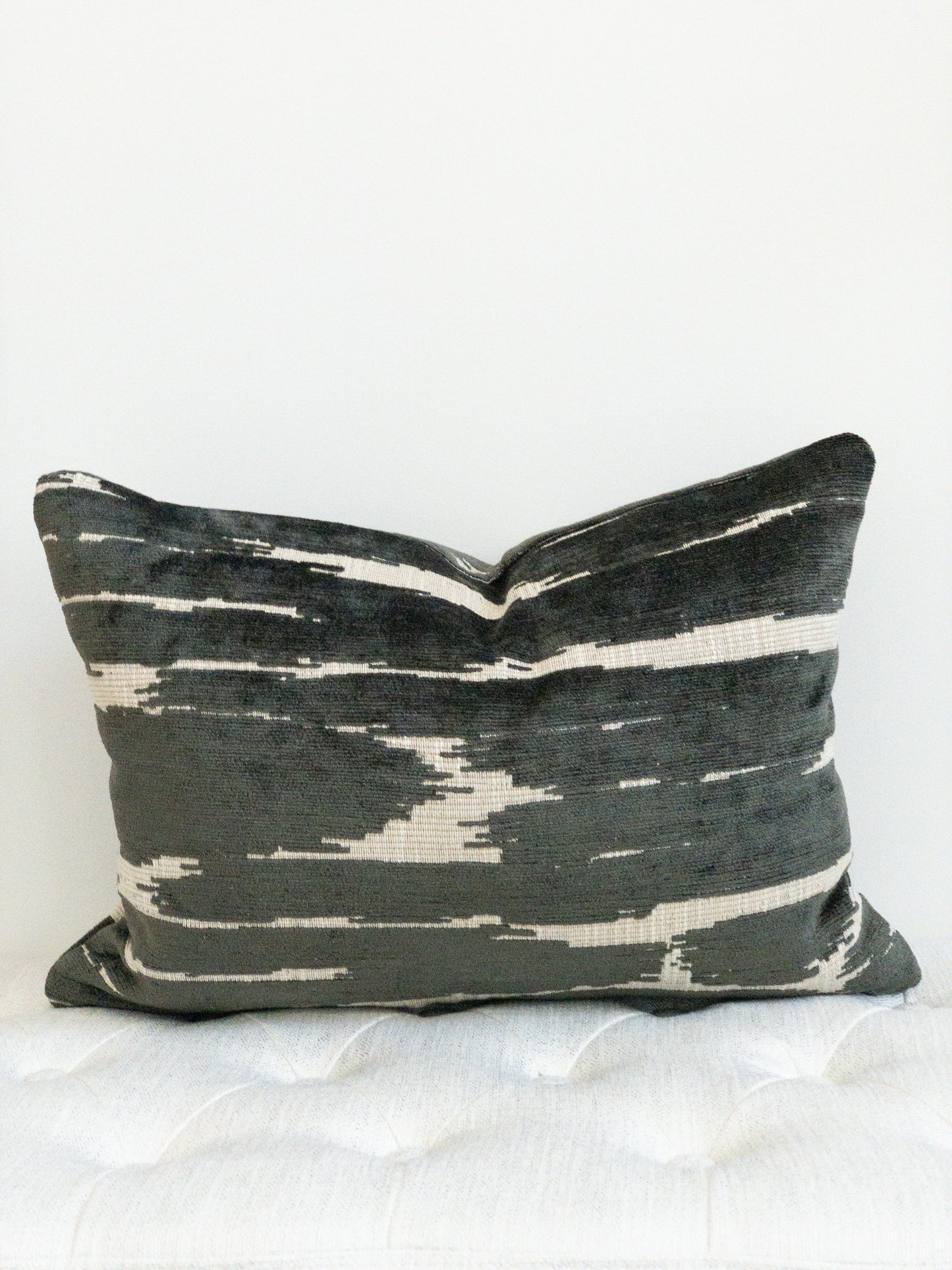 Black and beige chenille lumbar pillow. Black raised threads on flat beige background. Abstract placement of alternating colors.