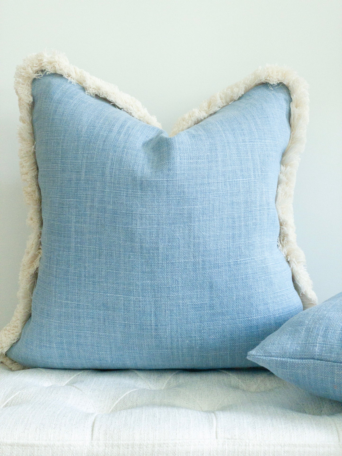 Light blue linen pillow with natural cotton brush fringe