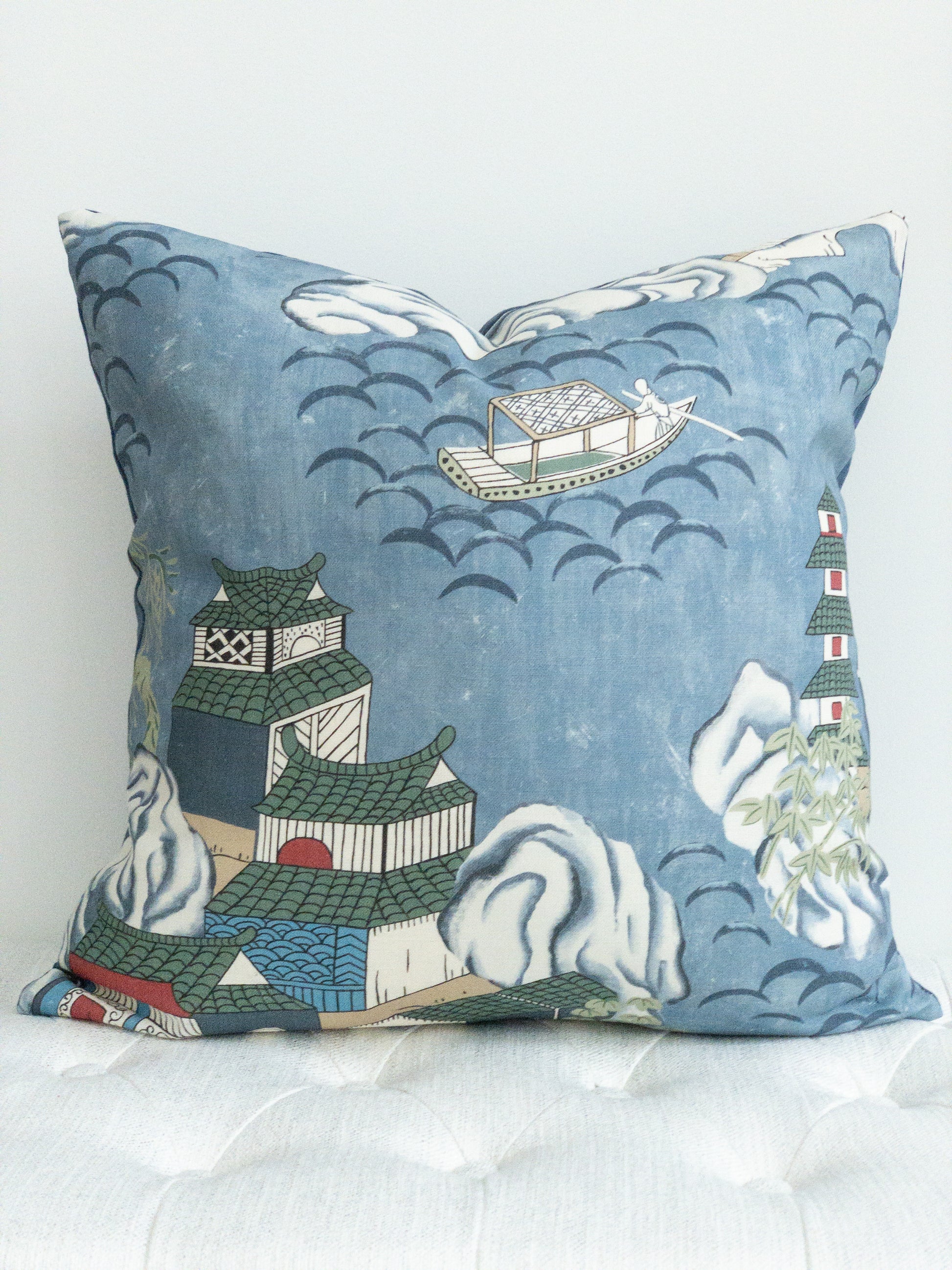 Square blue pillow with chinoiserie print of teahouses and boats on water