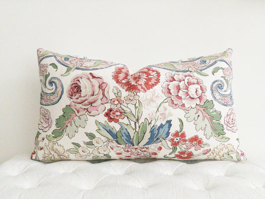 Multi color floral designer lumbar pillow.  Reds, pinks , blues and greens on a white background. 