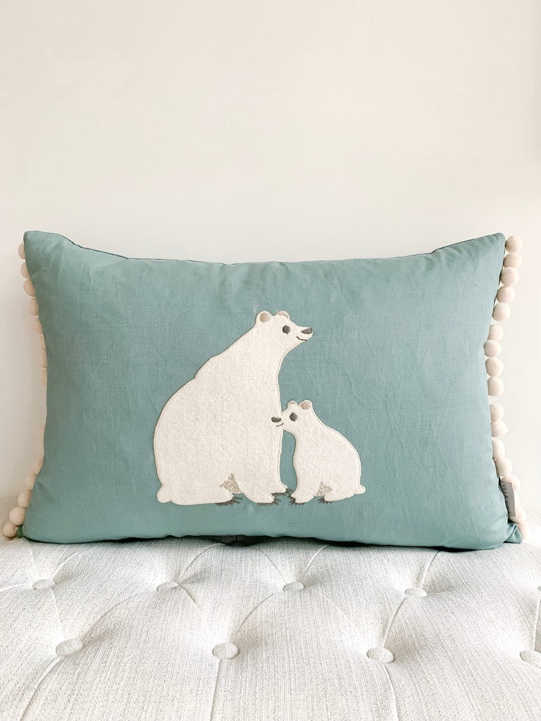 Blue decorative lumbar pillow with polar bear motif and pom poms