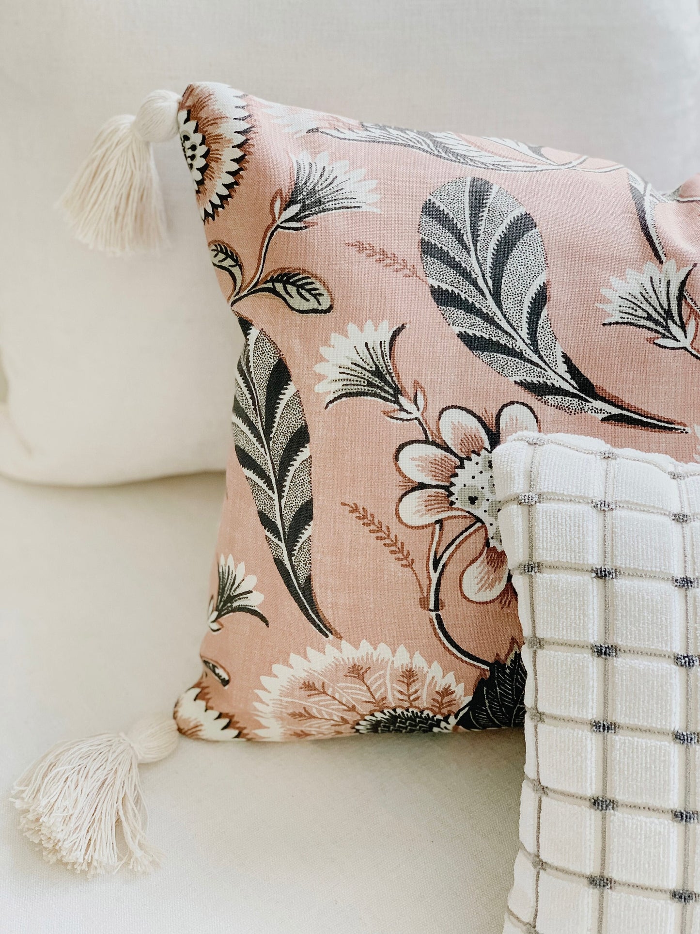 Decorative lumbar pillow in blush floral fabric with tassels on white sofa