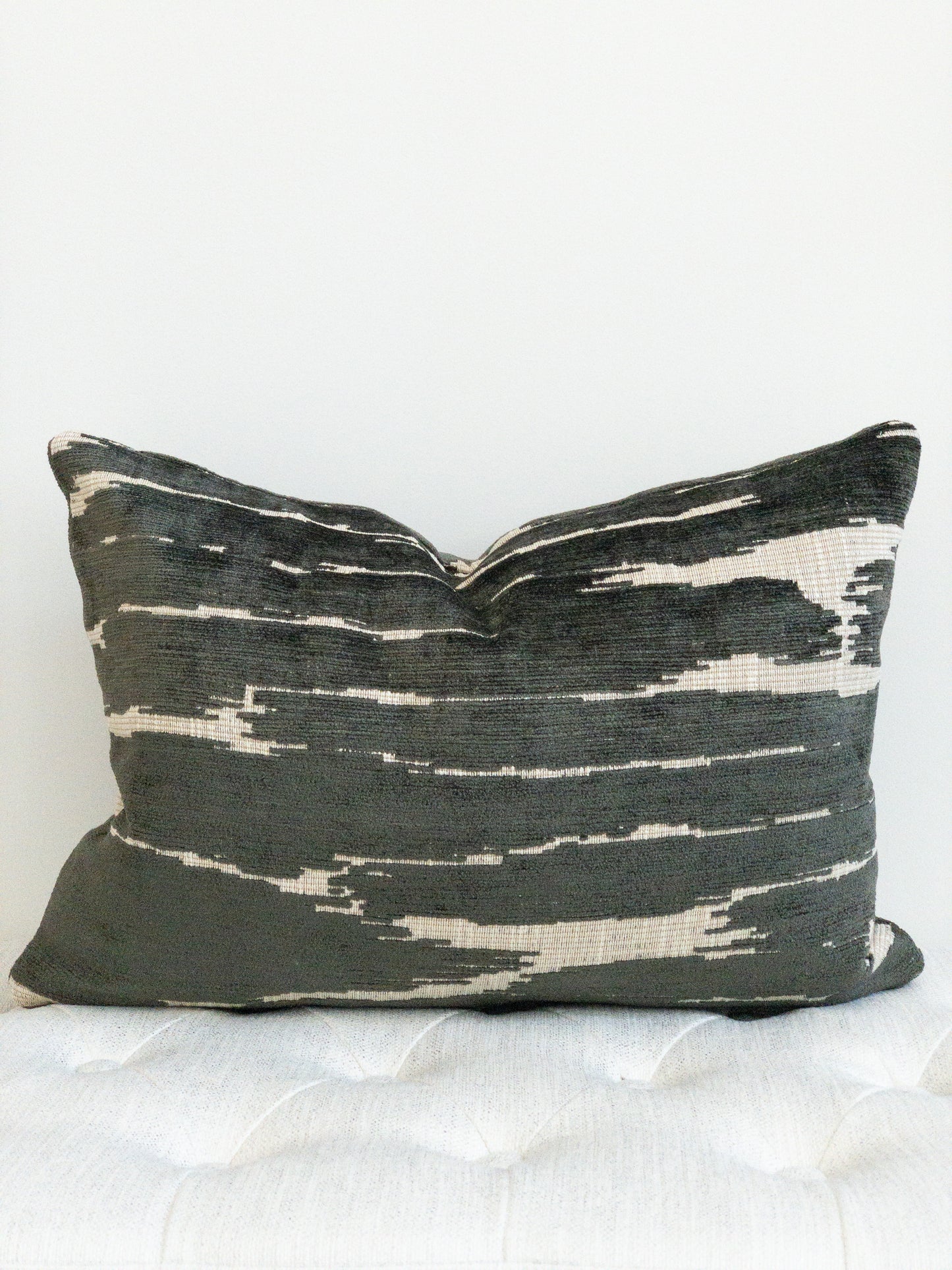 Black and beige chenille lumbar pillow. Black raised threads on flat beige background. Abstract placement of alternating colors.